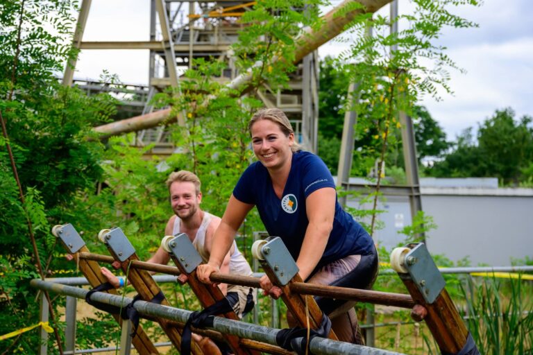 2 deelnemers aan ultimate warrior run aan het klimmen met een glimclach